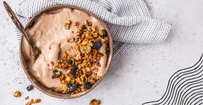 Breakfast smoothie bowl with granola and dried fruit, with golden spoon and napkin